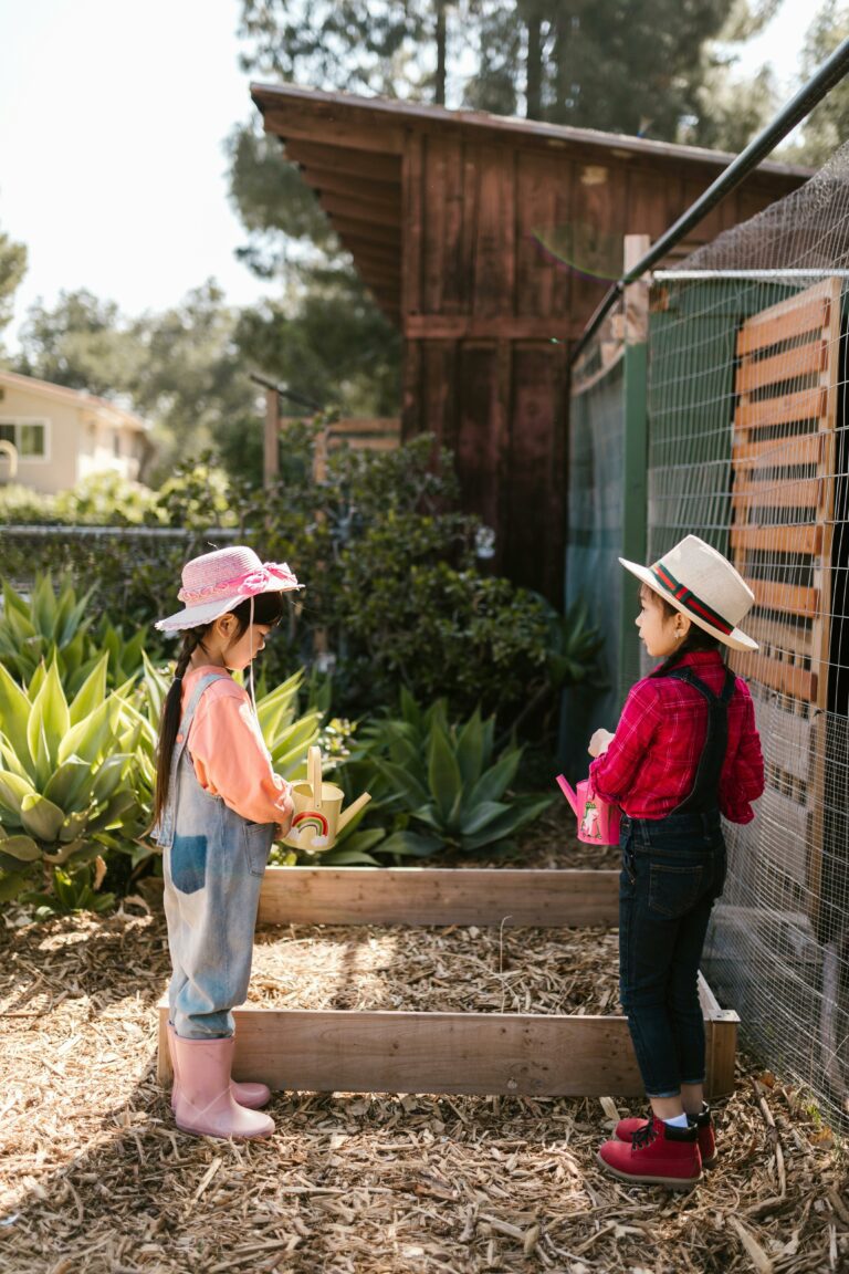 two kids standing over raised garden bed