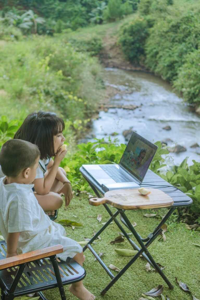 a couple of kids sitting at a table with a laptop